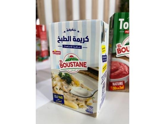 Une brique de crème de cuisson El Boustane est posée sur une table, avec d’autres produits alimentaires en arrière-plan.