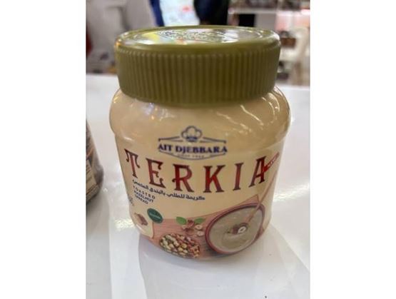 Un pot de crème de noisettes grillées, fermé par un couvercle vert, posé sur une table.