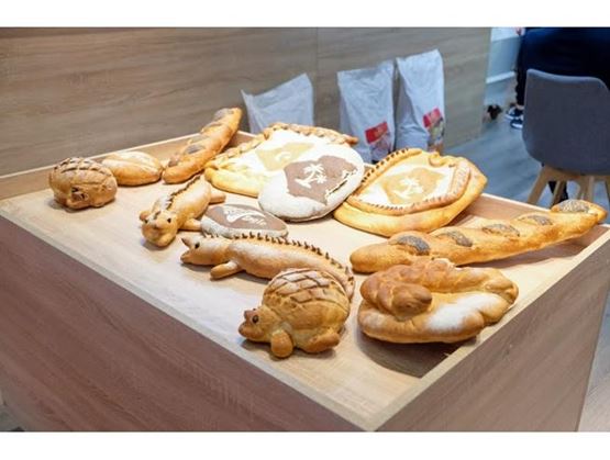 Des pains décoratifs en forme d’animaux et de symboles sont exposés sur une grande table en bois.