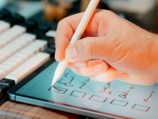 Main tenant un stylo tactile et écrivant sur une tablette tactile