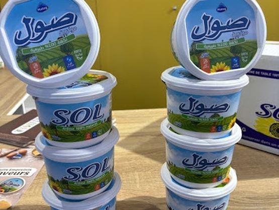 Pots empilés de margarine ou de matière grasse végétale de marque SOL, présentés sur un stand, avec un emballage illustré de champs et de tournesols.