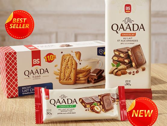 Cette image présente une sélection de produits "Qaada", avec des barres de chocolat au lait et aux amandes, ainsi que des biscuits au chocolat au lait.