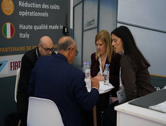 Professionnels réunis autour d’une table pour échanger lors d’un rendez-vous d’affaires sur un salon.