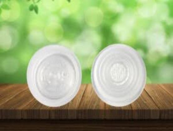 Deux couvercles blancs présentés sur une surface en bois, avec un arrière-plan vert flou évoquant la nature.