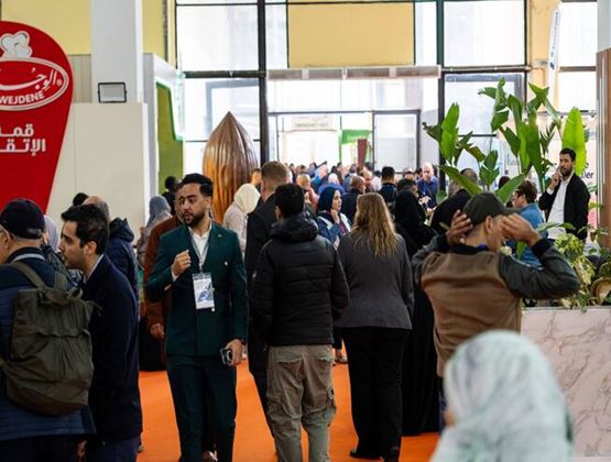 Allée fréquentée d’un salon professionnel avec visiteurs et exposants échangeant sur les stands.