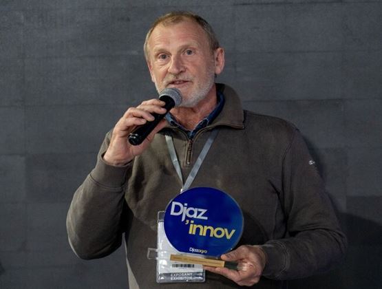 Un exposant prend la parole au micro en tenant un trophée Djaz’Innov.