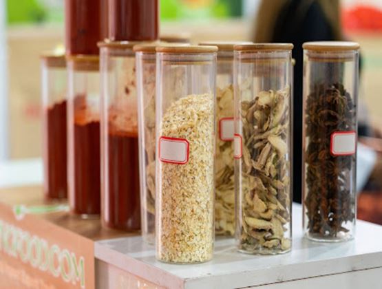 Tubes transparents contenant différentes épices et plantes séchées sur un stand alimentaire.