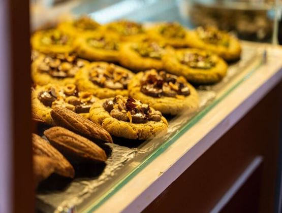 Biscuits garnis de chocolat et de fruits à coque présentés dans une vitrine.