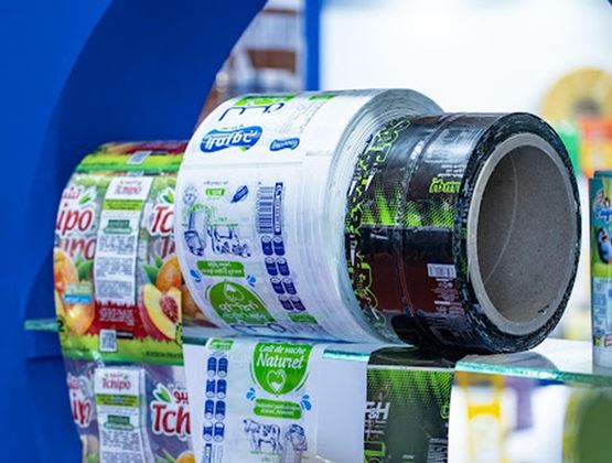 Bobines de films d’emballage imprimés pour produits alimentaires et boissons, présentées sur un stand.