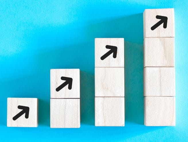 Illustration d'une croissance progressive avec des blocs en bois et des flèches montantes sur un fond bleu.