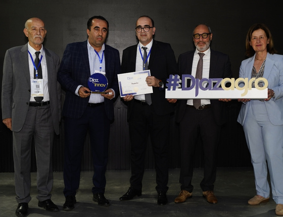 Group of professionals in suits receiving an award at an event, holding a trophy and a #Djazagro sign