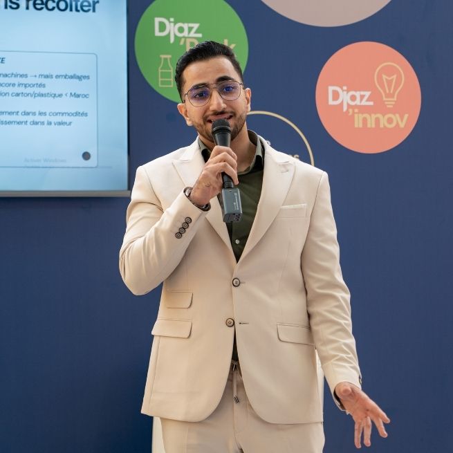 Intervenant prenant la parole avec un micro sur l’espace d’animation de Djazagro, devant un fond aux couleurs de Djaz’Innov dédié à l’innovation et à l’entrepreneuriat dans l’industrie agroalimentaire.