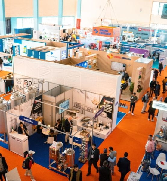 Vue d'ensemble d'un salon professionnel avec des stands d'exposants et des visiteurs en déplacement.
