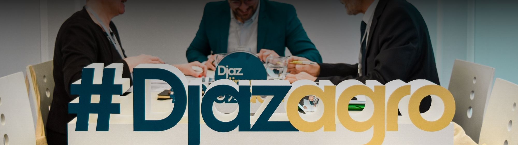 Trois membres du jury en pleine réunion lors du salon Djazagro, avec une pancarte #Djazagro au premier plan.