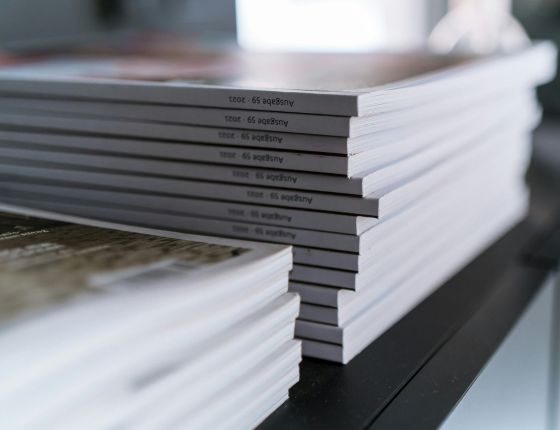 Stack of brochures or documents neatly arranged, representing press releases or professional publications.